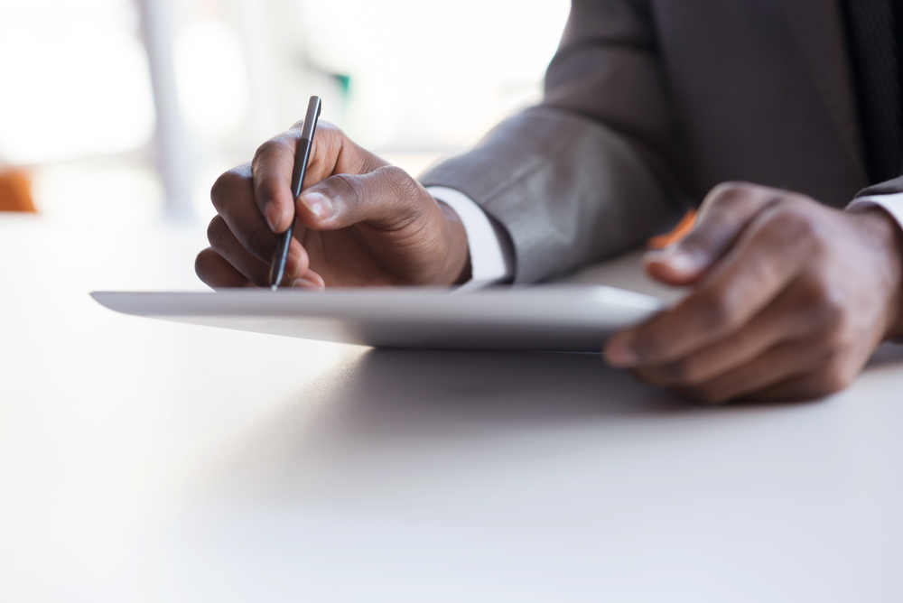 Black businessman writing on tablet using stylus