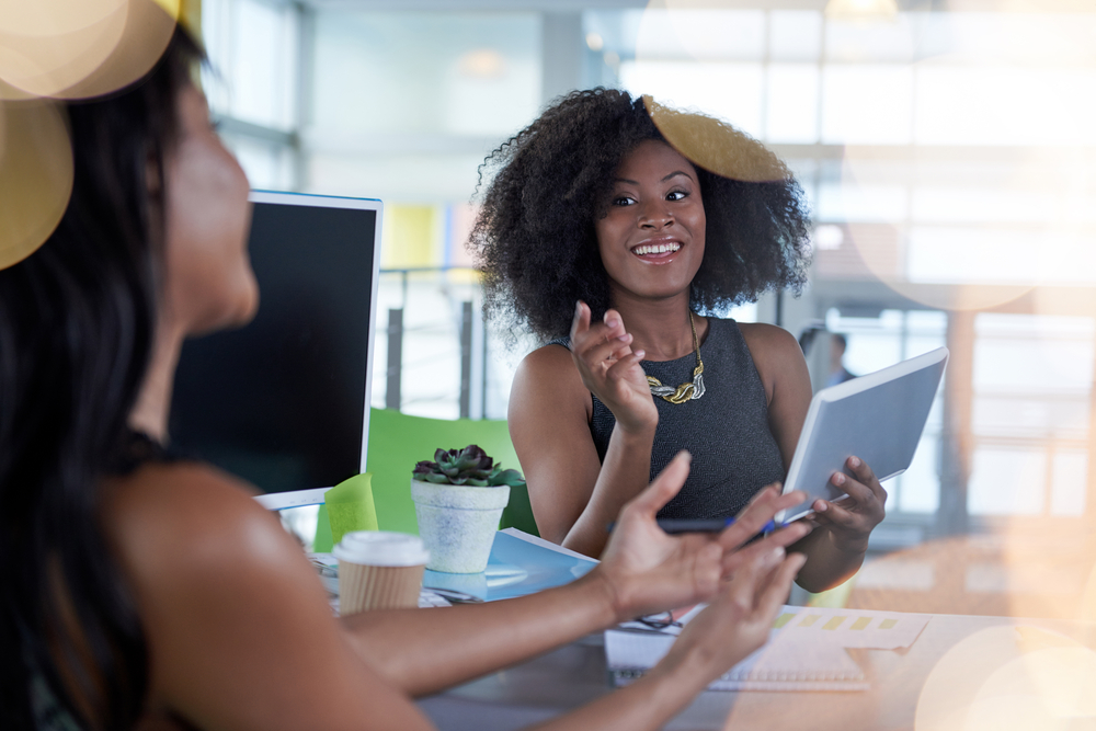 Two young women in tech collaborating on a project at a table